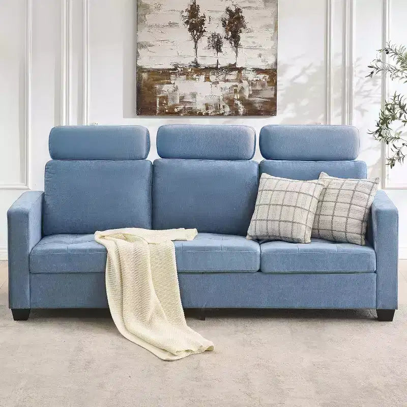 Blue sofa with plaid pillows and a blanket in a living room setting.